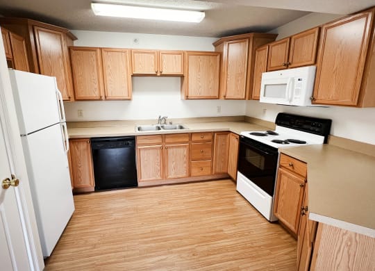 an empty kitchen with wooden cabinets and white appliances  at Walton Ridge Apartments, Walton, Kentucky