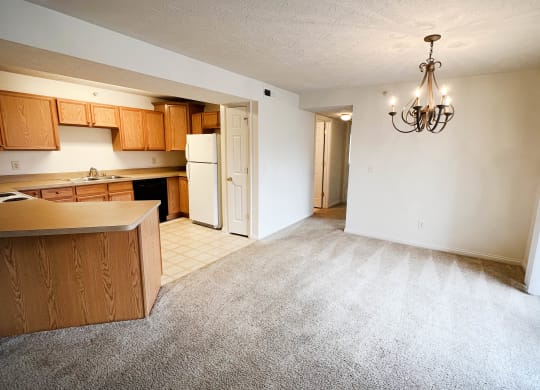 an empty living room with a kitchen and a chandelier  at Walton Ridge Apartments, Walton, KY, 41094