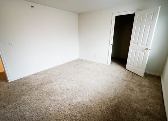 an empty room with a carpeted floor and a white door  at Walton Ridge Apartments, Walton