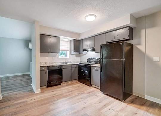 A kitchen with a refrigerator, oven, and sink.
