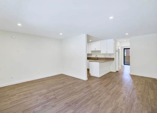 A spacious room with wooden flooring and white walls.