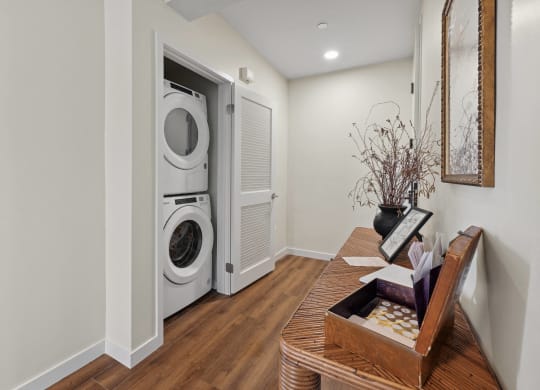 a living room with a table and a washer and dryer in a door The Baxter in Los Angeles, CA 90028