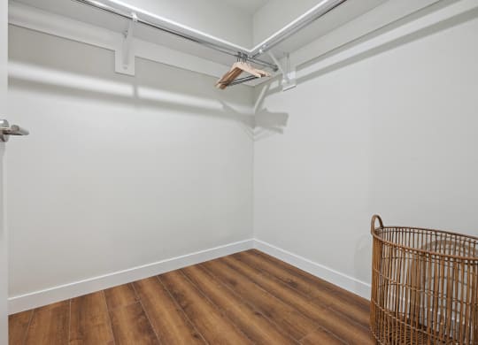 a room with white walls and wooden floors and a wire basket on the wall The Baxter in Los Angeles, CA 90028