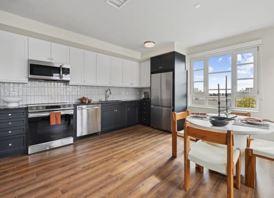 a kitchen with black appliances and a table and chairs The Baxter in Los Angeles, CA 90028