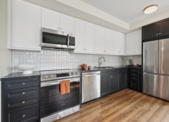 a kitchen with black and white cabinets and stainless steel appliances The Baxter in Los Angeles, CA 90028