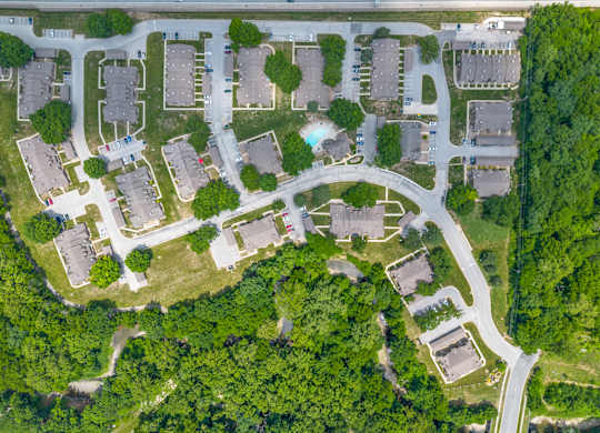 A bird's eye view of a residential area with houses, roads, and greenery.