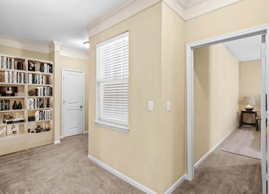 A hallway with crown molding, a window, and built in book shelf at Avignon Apartments in Olathe, Kansas