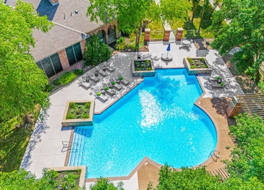 Aerial view of an outdoor swimming pool with lounge seating and beautiful landscaping.