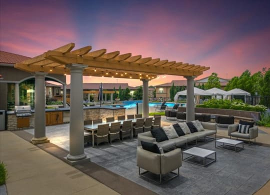 a patio with couches and chairs under a wooden canopy