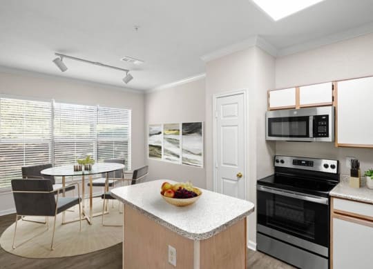 A kitchen and dining area with large windows, track lighting, stainless steel microwave and appliances, pantry closet, and a kitchen island.