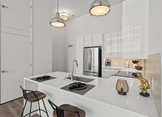 a kitchen with white cabinetry and a large white island with a sink and two stools