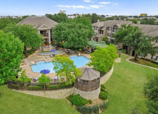 an aerial view of an apartment complex with a large pool in the middle of the yard at The Clairborne Apartment Homes, Grand Prairie