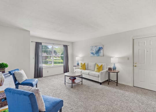 a living room with a white couch and blue chairs and a white door with a gold knob at Pebblebrook, Overland Park, KS