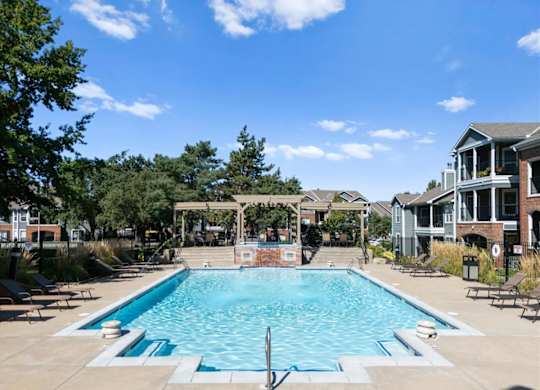 A large swimming pool surrounded by trees and a building. at Somerset Oaks Apartment Homes, Kansas, 66062