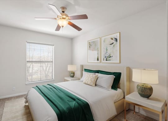 A bedroom with a ceiling fan and window.