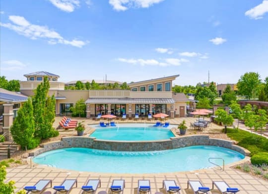 a swimming pool with chairs around it in front of a hotel