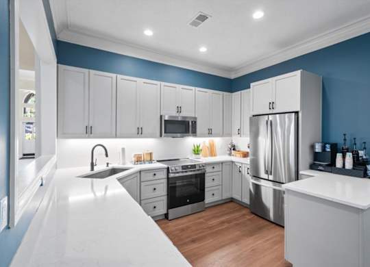 A modern kitchen with stainless steel appliances and white countertops.at The Claremont Apartment Homes, Overland Park