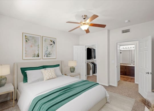 A master bedroom with a large walk in closet, an attached master bathroom and ceiling fan.