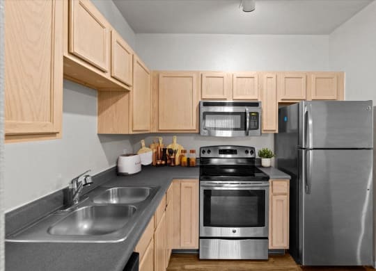 a kitchen with stainless steel appliances and wooden cabinets at Stonepost Lakeside, Olathe, KS, 66062
