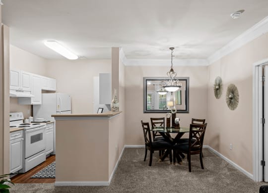 a dining area with a table and chairs and a kitchen in the background at Creekside, Overland Park, Kansas