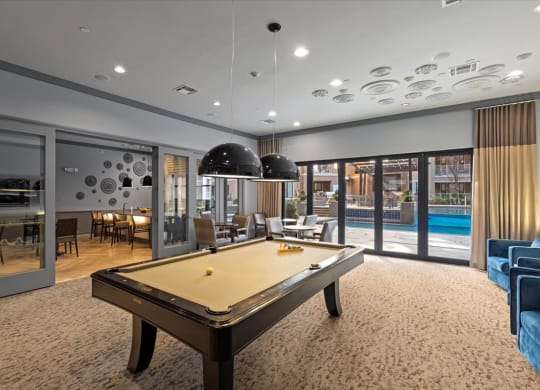 a pool table in a living room next to a swimming pool