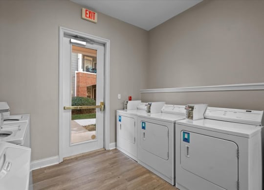 A laundry room with a washer and dryer on the right and a door leading outside.