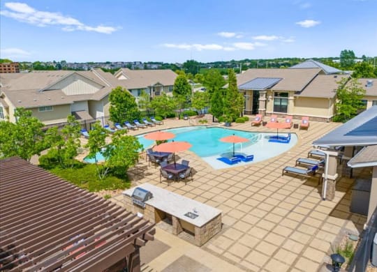 an aerial view of an outdoor pool with tables and umbrellas