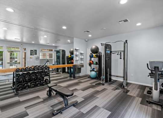 A gym with a variety of equipment including a squat rack, dumbbells, and a bench.at Crowne Chase Apartment Homes, Overland Park, KS
