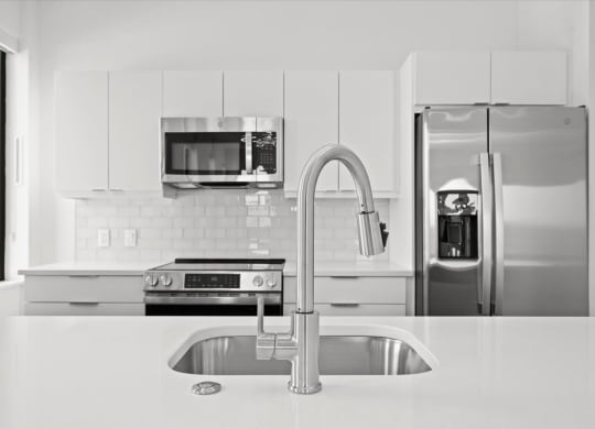 a white kitchen with stainless steel appliances and a sink