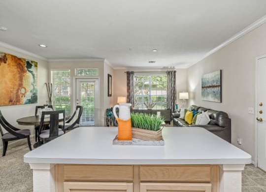 a kitchen with a center island next to a living room with a couch and a table
