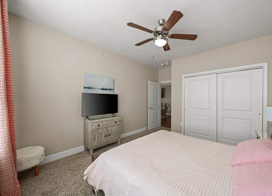 A bedroom with a bed, dresser, and television.