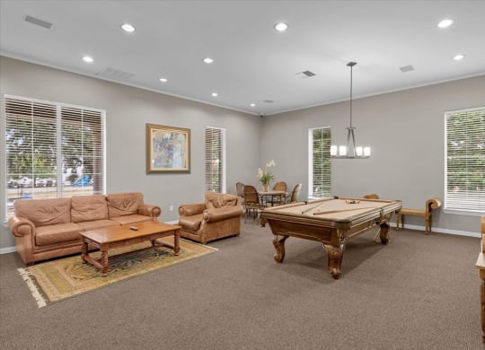 a game room with a pool table and couches at The Clairborne Apartment Homes, Grand Prairie, TX 
