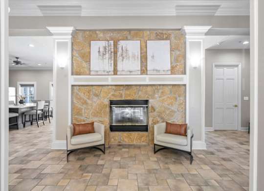 A living room with a stone fireplace and two chairs. at Somerset Oaks Apartment Homes, Olathe, KS