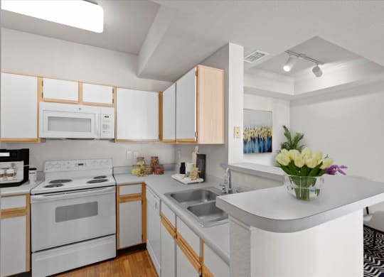 An open kitchen with white appliances, grey countertops, and white storage cabinets.