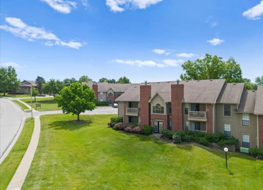 an apartment building with a green lawn and trees at Highland Park Apartment Homes, Kansas, 66214