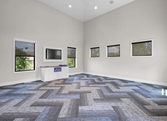 an empty living room with a tv and windows