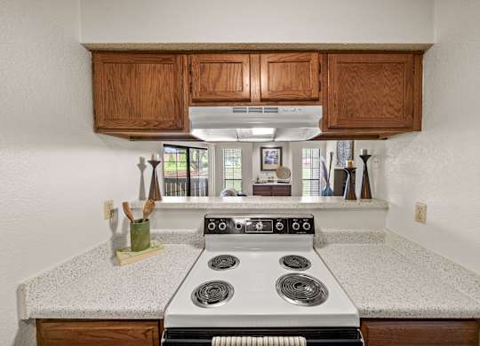 A kitchen with a stove top oven and wooden cabinets.
