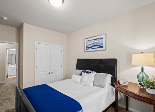 a bedroom with a bed and a nightstand with a lamp at Creekside, Overland Park, 66213