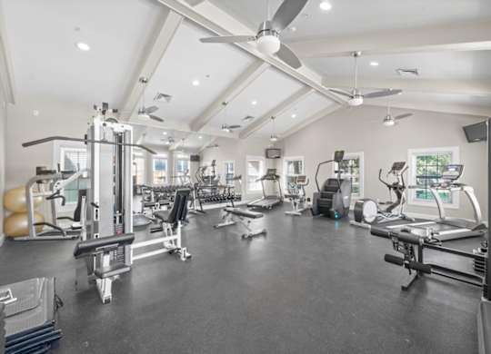 A spacious gym with various exercise equipment and a ceiling fan. at Somerset Oaks Apartment Homes, Olathe, Kansas