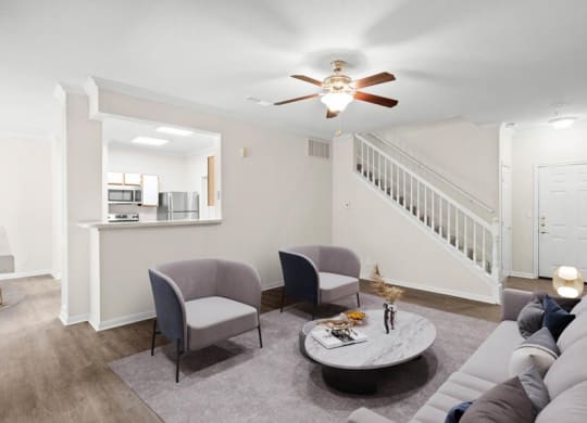 A living room with a ceiling fan and a staircase.