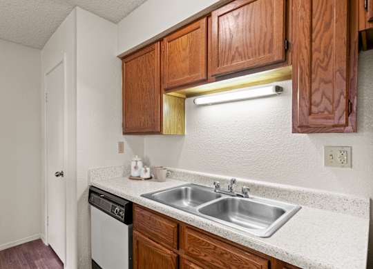 A kitchen with a white counter top and wooden cabinets.