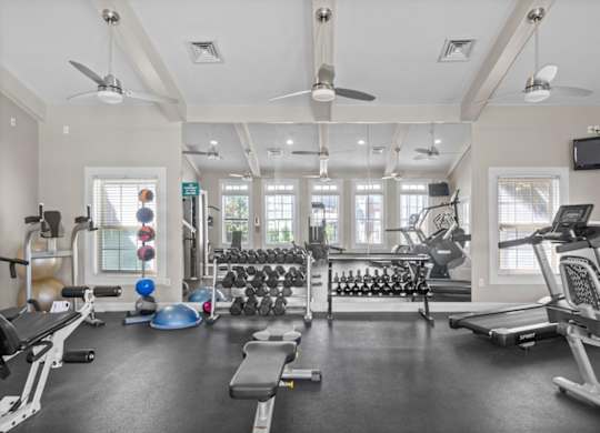 A spacious gym with a variety of equipment including treadmills, weights, and a television. at Somerset Oaks Apartment Homes, Olathe, KS