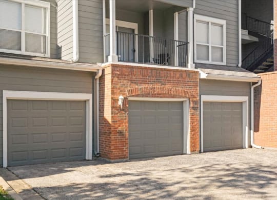 Two garage doors are closed in front of a brick wall.