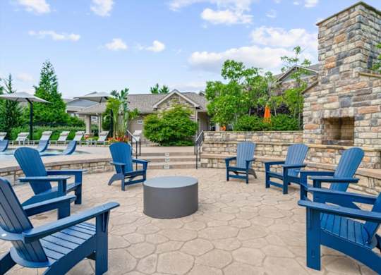 A patio with blue chairs and a fireplace.