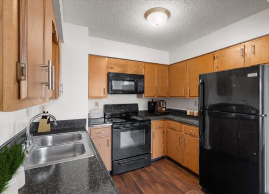 a kitchen with black appliances and wooden cabinets at Deerfield Apartments, Olathe, Kansas