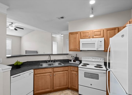 A spacious kitchen with oak cabinets, white appliances, track lighting, and plenty of counterspace.
