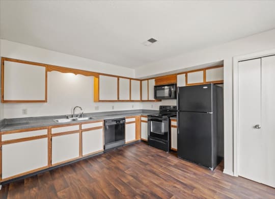 a kitchen with white cabinets and a black refrigerator at Deerfield Apartments, Olathe, KS