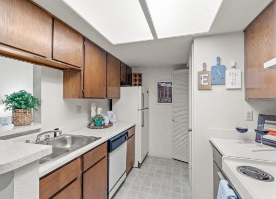 a kitchen with white appliances and wooden cabinets at Pebblebrook, Overland Park