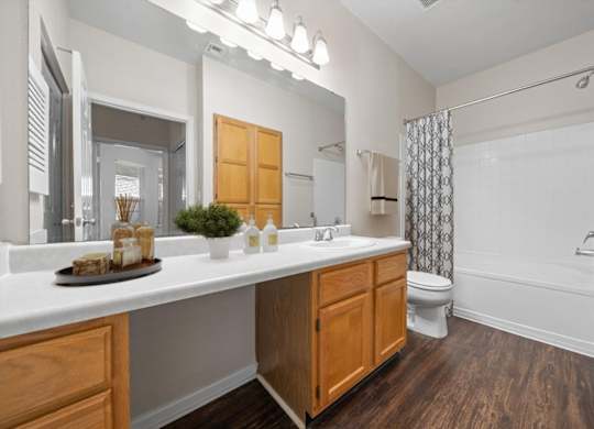 A bathroom with a white countertop and wooden cabinets. at Somerset Oaks Apartment Homes, Olathe, Kansas