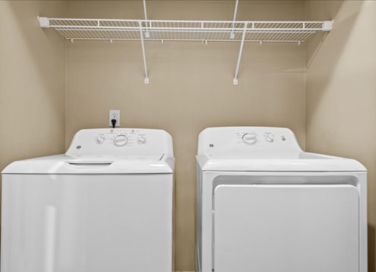 two washers and dryers in a laundry room with a rack on the wall at Avignon Apartment Homes, Olathe, KS, 66062